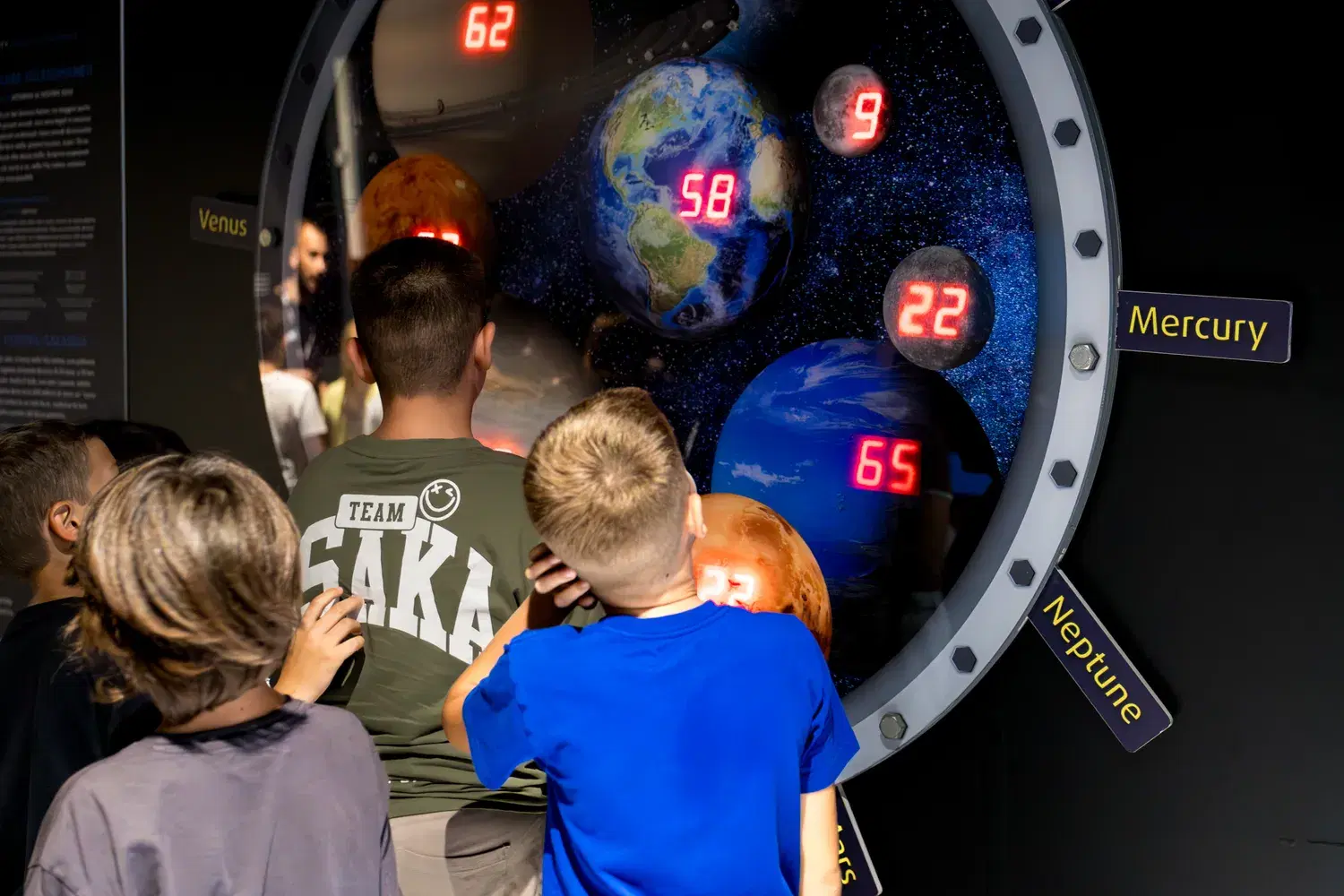 Children in front of the planets porthole, the weights lit in red
