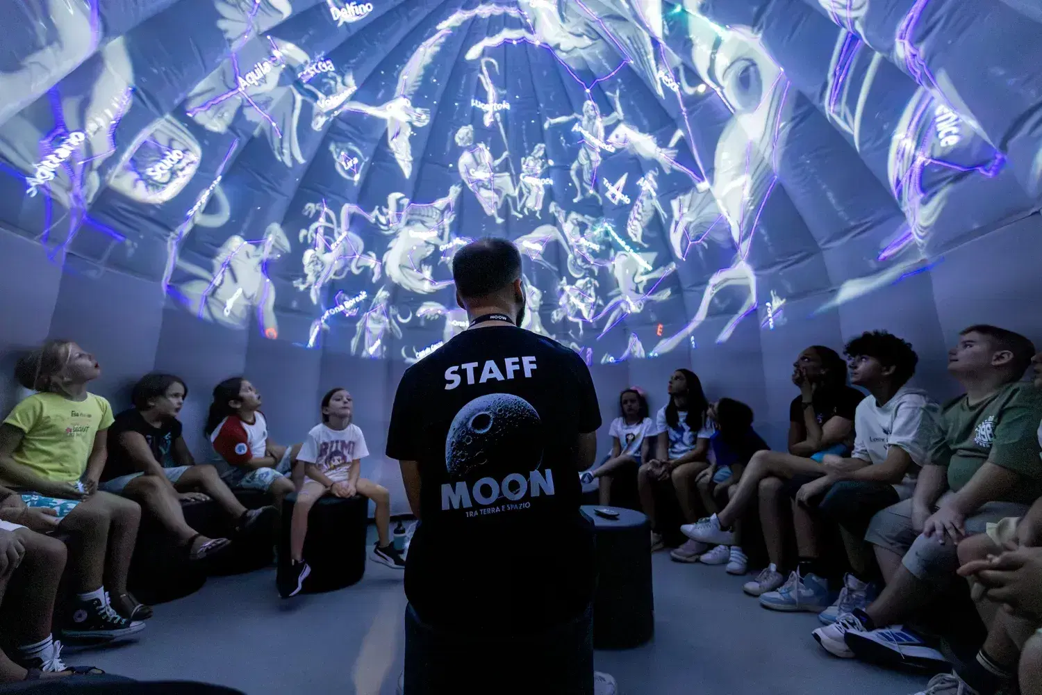 The planetarium with constellations projected on the dome and the students sitting around the operator