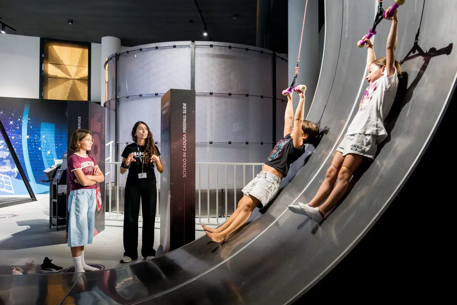 Young visitors hang from the ropes as they climb the big curved wall