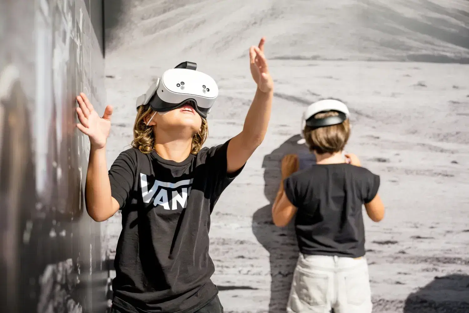 A girl wearing a headset reaches out her hands in front of the lunar wall