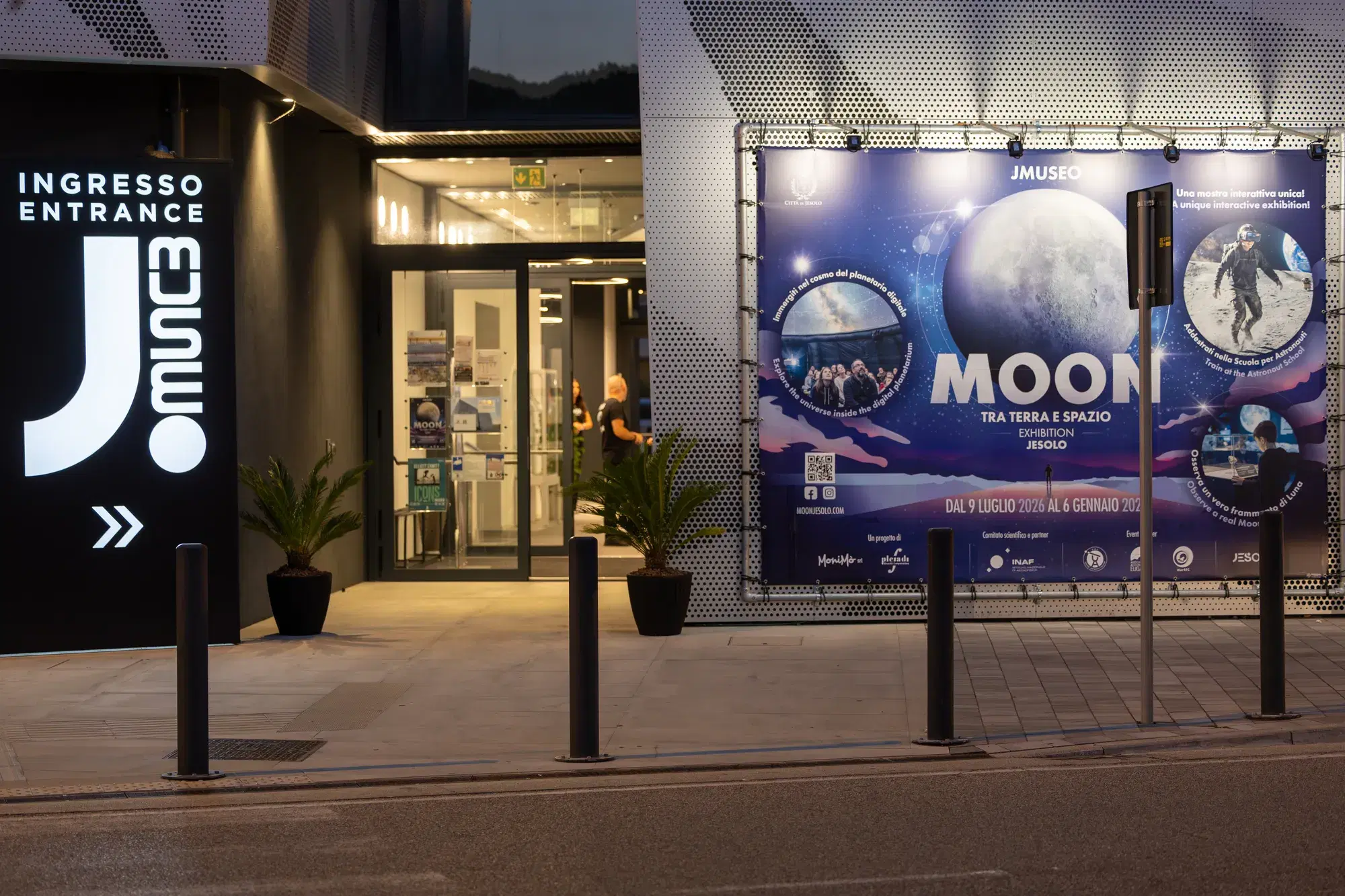 L'ingresso del JMuseo di sera, con il grande banner della mostra MOON illuminato