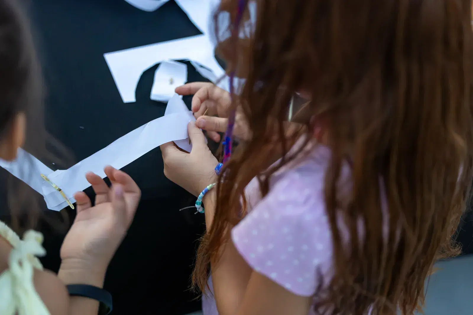Due bambine ritagliano strisce di carta durante un'attività per bambini