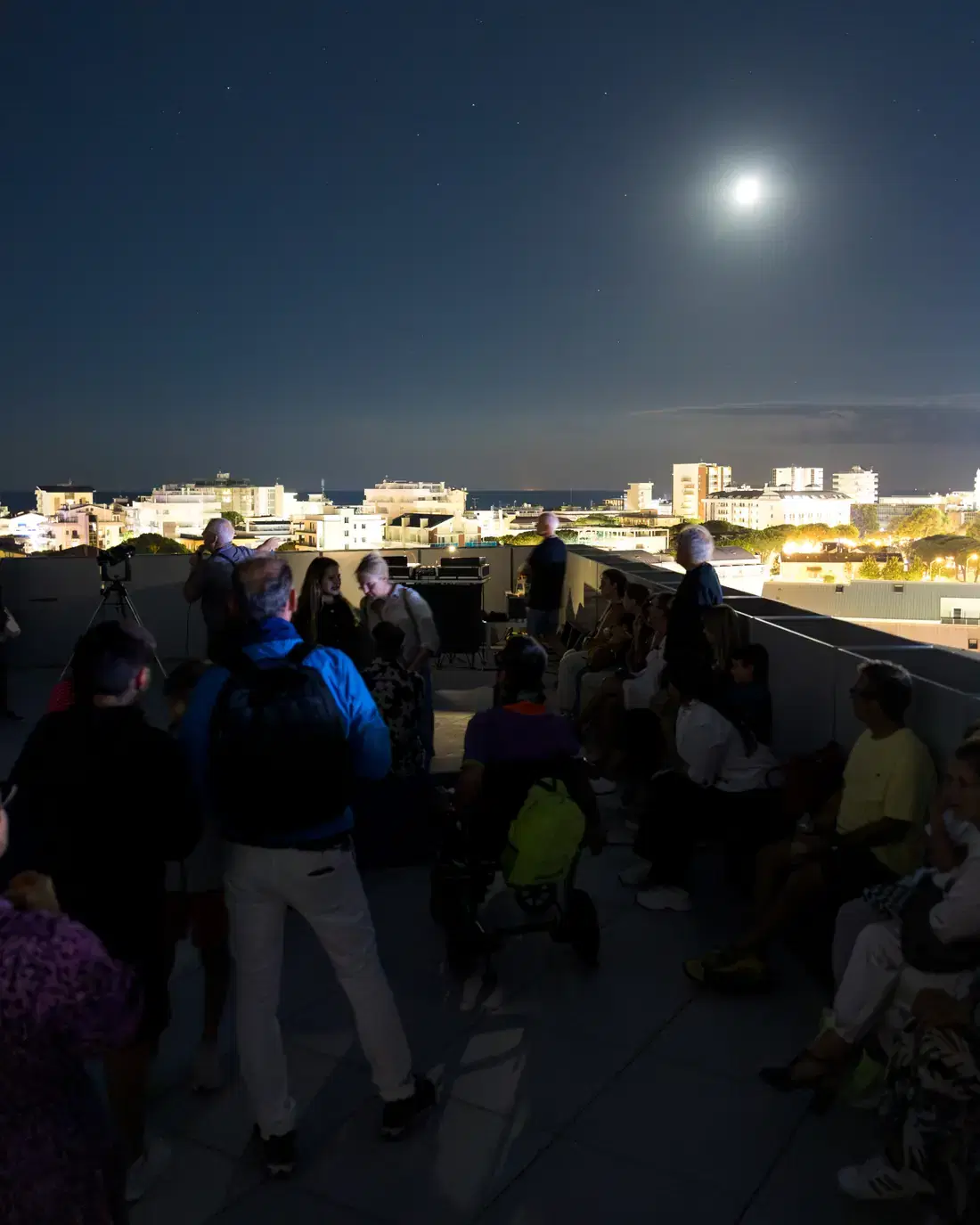 Il pubblico sulla terrazza del JMuseo sotto la Luna, con le luci di Jesolo sullo sfondo
