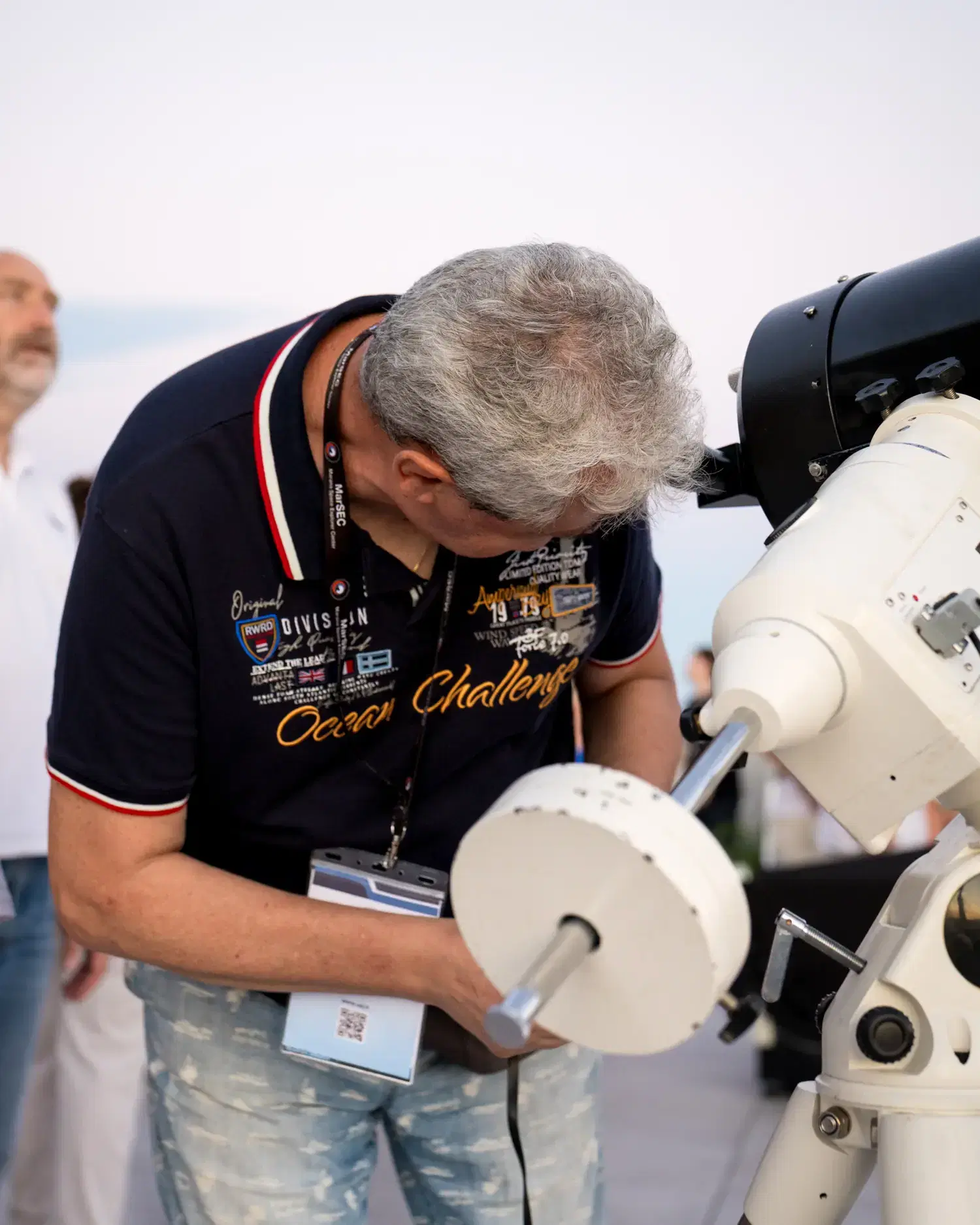Un socio dell'Unione Astrofili Italiani monta il contrappeso di un telescopio sulla terrazza, con il cielo ancora chiaro