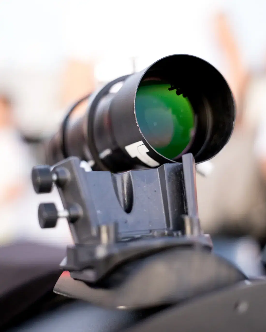 L'obiettivo di un telescopio rifrattore in primo piano, con il riflesso verde del trattamento antiriflesso