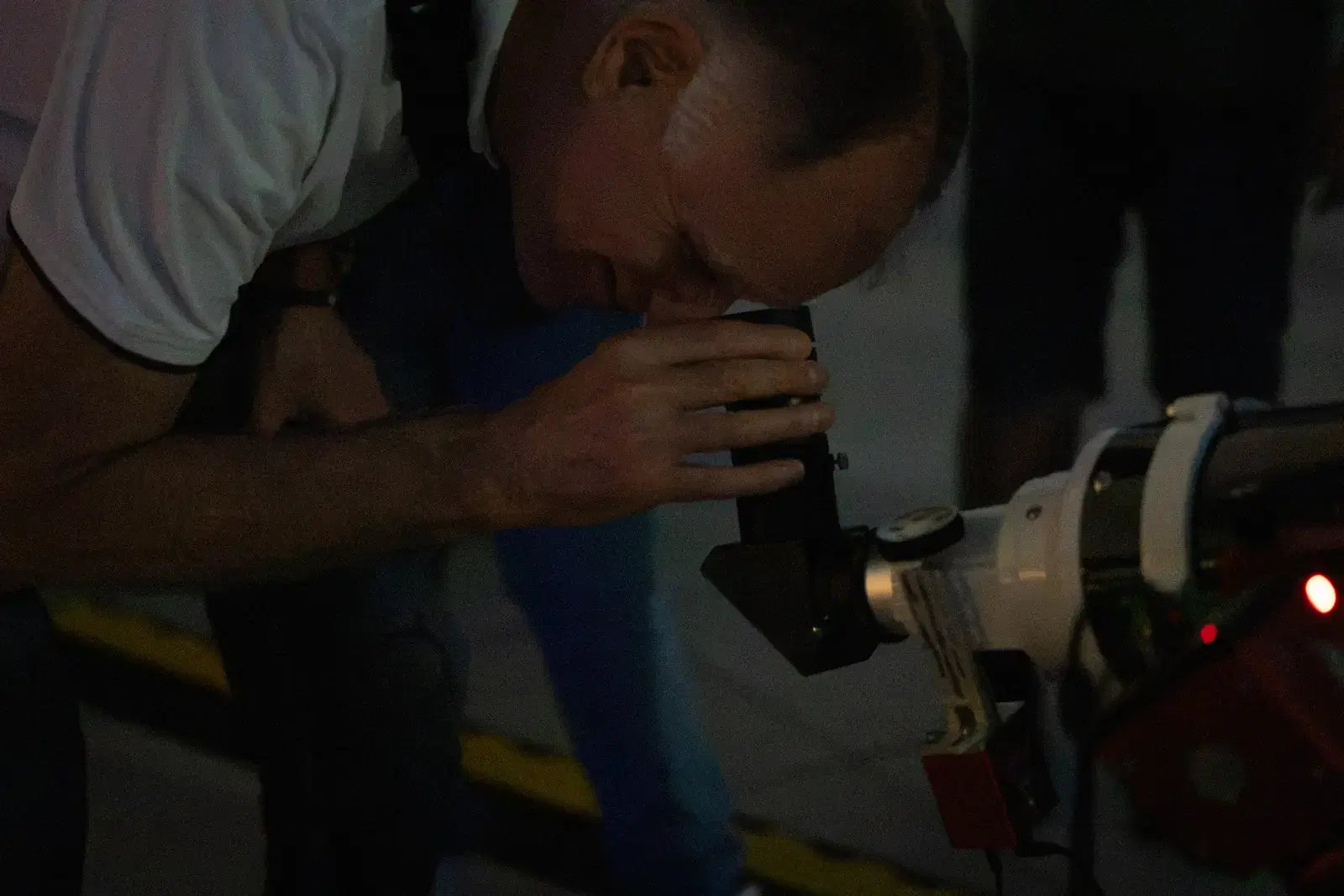Un uomo si china sull'oculare del telescopio nel buio della terrazza